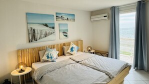 A bedroom with a wooden bed, a nightstand, a lamp, and artwork on the wall. - Generous exclusive holiday home in a dream location right on the beach with great views (Gruissan)