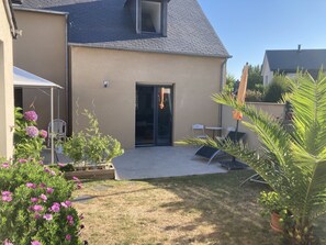 Een huis met een patio, een schuifpui en zitplaatsen buiten.
