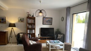 A living room with a sofa, a coffee table, a bookshelf, a TV, and a lamp. - 3-STAR FISHERMAN'S STYLE HOUSE IN CANCALE 300M FROM THE PORT QUIET AREA (Cancale)