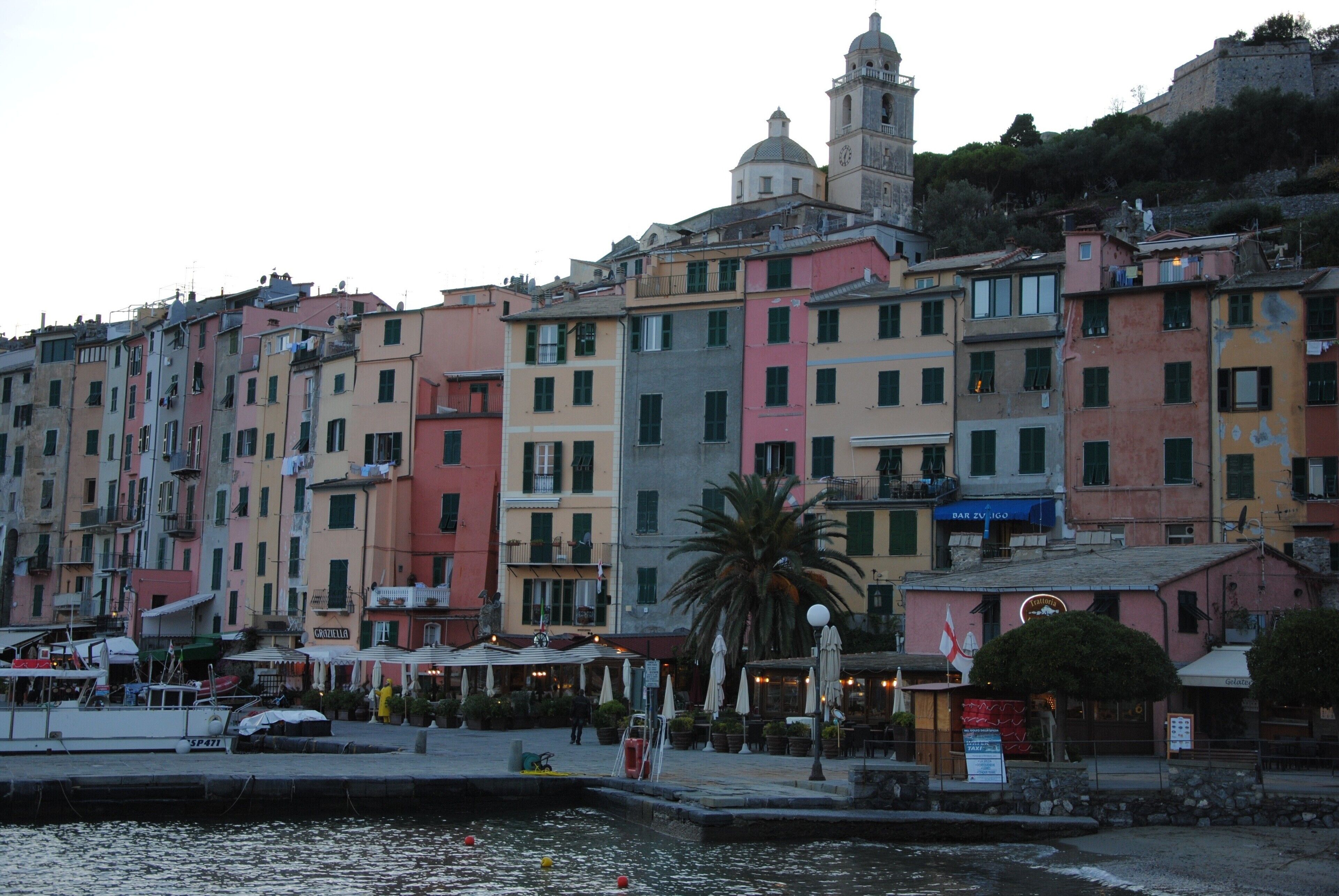 Zona costera con edificios coloridos, un muelle y una torre destacada.