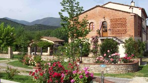 Un edificio rústico con fachada de ladrillo, rodeado de un jardín con flores florecientes y un camino de piedra.