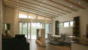 Een modern interieur met een eethoek, een ingebouwde open haard en grote ramen.
