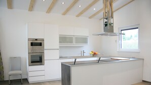 Een moderne keuken met inbouwapparatuur, een groot kookeiland en een raam dat voor natuurlijk licht zorgt.