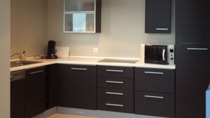 A modern kitchen with dark cabinetry, a white countertop, a built-in microwave, and a pendant light.