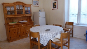 Ein Essbereich mit einem runden Tisch, Holzstühlen, einem Schrank mit Glastüren und einem Kühlschrank.