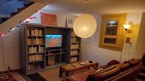 Una sala de estar acogedora con una estantería, un televisor, un sofá y una alfombra estampada.