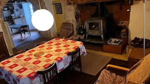 Una sala de estar acogedora con una mesa de comedor, sillas, una chimenea y una cocina visible a través de un arco.