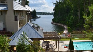 A lakeside view with a pool area, outdoor seating, and a dock. - BOLTON COVE: 10 Cricket Ln. Pool, beach, playground, boat rental - 4 homes avail (Lake Martin)