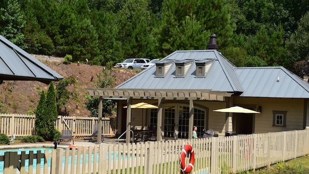 A pool area with a wooden fence, a lifebuoy, and a covered patio with outdoor furniture. - BOLTON COVE: 10 Cricket Ln. Pool, beach, playground, boat rental - 4 homes avail (Lake Martin)