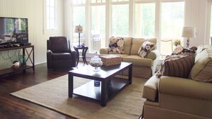 A living room with a sofa, armchair, coffee table, and television. - BOLTON COVE: 10 Cricket Ln. Pool, beach, playground, boat rental - 4 homes avail (Lake Martin)