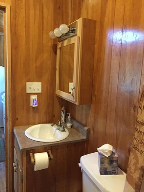 Une salle de bain en bois avec un lavabo, un miroir et du papier toilette.