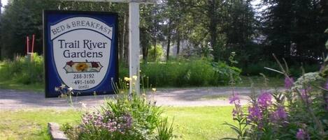 A sign for Trail River Gardens, a bed and breakfast, with contact numbers.