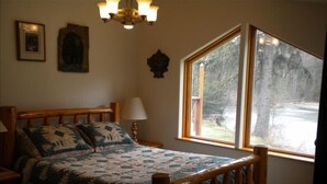 Een slaapkamer met een houten bed, een groot raam en een kroonluchter.