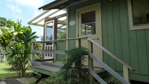 A green building with a porch, a door, and a window.