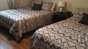 Un dormitorio con dos camas, un ventilador de techo, un reloj de pared y una ventana con cortinas.