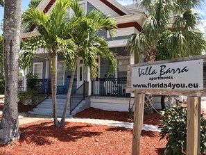 Villa Barra apartments with a signboard, a staircase, and a dog in the background.