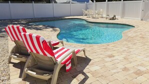 A swimming pool with two lounge chairs and a table, surrounded by a white fence and a paved patio. - Book now and save: great deals for your next getaway! (Fort Myers)