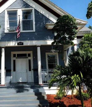 A two-story house with a porch, a flag, and a mailbox.