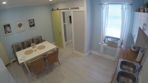 Cocina compacta con comedor, horno empotrado y ventana con cortinas.
