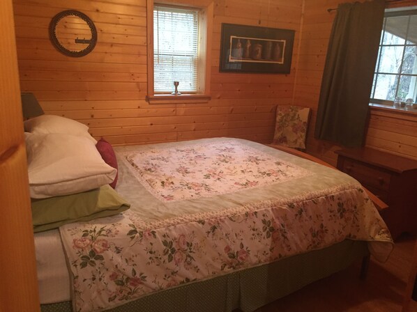A wooden room with a bed, a window with blinds, a framed picture on the wall, and a wooden dresser. - Hickory Grove Cabin On 8 Acres With Private Fishing Pond. (Rockbridge)