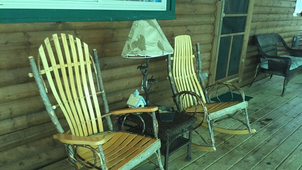A wooden rocking chair and a chair with a lamp on a porch with wooden flooring. - Hickory Grove Cabin On 8 Acres With Private Fishing Pond. (Rockbridge)