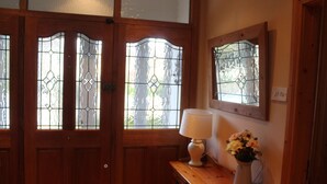 A wooden door with stained glass windows, a white lamp, and a vase with flowers on a wooden table. - Cois Ba House (Dublin)