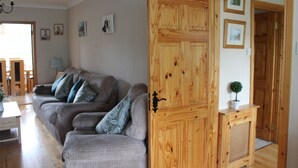 A living room with a grey sofa, wooden door, and framed pictures on the wall. - Cois Ba House (Dublin)