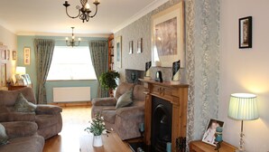A cozy living room with a fireplace, two sofas, a coffee table, and a chandelier. - Cois Ba House (Dublin)