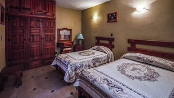 Un dormitorio con dos camas, armario de madera, mesitas de noche, lámpara y aplique de pared.