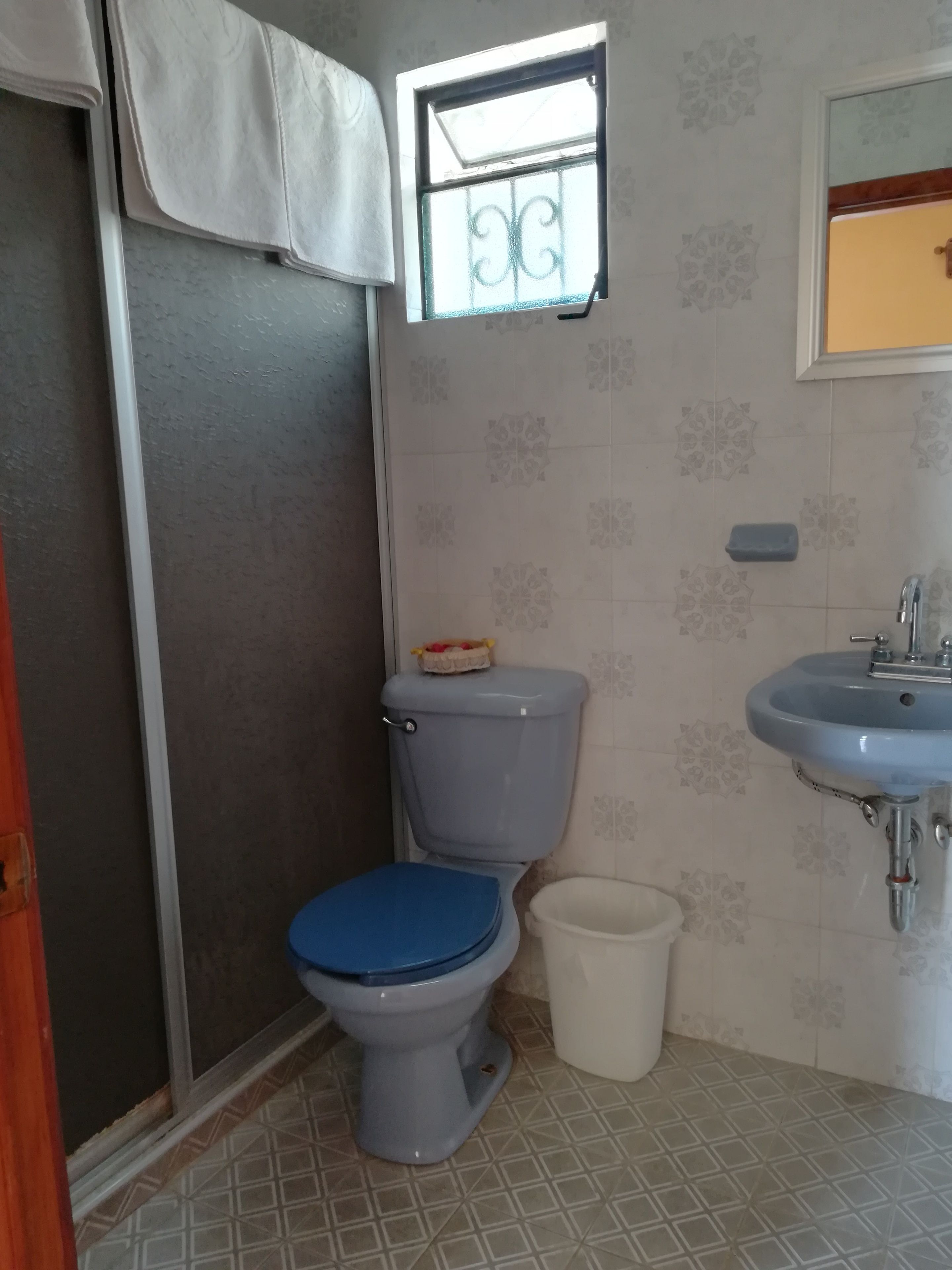 A bathroom with a toilet, a sink, and a small window.