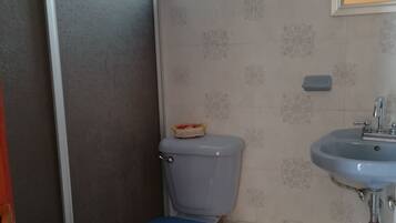 Un baño con inodoro, lavamanos y un pequeño ventanal.