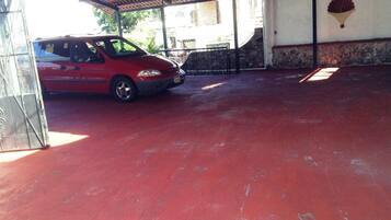 Un área de estacionamiento techada con un coche rojo aparcado en su interior.