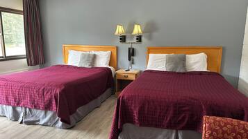 A hotel room with two beds, a nightstand with lamps, and a window with curtains.