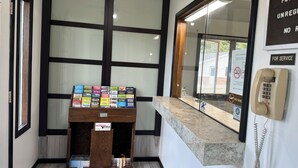 A reception desk with a display of books, a telephone, and a window with blinds. - Skyview Motel (Prairie du Sac)