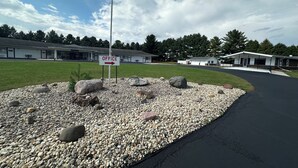 A building with an 'OFFICE' sign, a flagpole, and a gravel area with rocks. - Skyview Motel (Prairie du Sac)