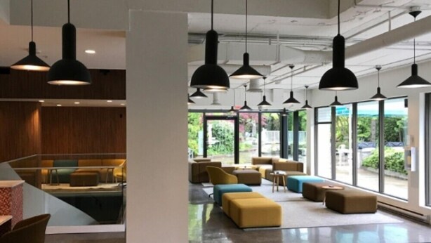 A modern lobby with a seating area, large windows, and hanging pendant lights. - Backpacker College at EC Vancouver: APT Living (Vancouver)