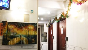 A hotel corridor with a painting of a sunset landscape, a trash bin, and a washing machine. - Safari Hotel (Kowloon)