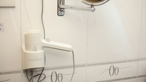 A bathroom with a white wall, a mirror, a white electric toothbrush, and a towel rack. - Safari Hotel (Kowloon)