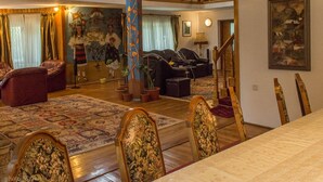 A spacious living room with a high ceiling, a dining area with a wooden table and chairs, and a staircase leading to an upper level. - Vila Flora Viseu de Jos (Viseu de Jos)