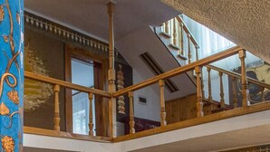 A spacious room with a high ceiling, a wooden staircase, and a dining area with a patterned rug. - Vila Flora Viseu de Jos (Viseu de Jos)