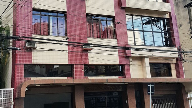 Un edificio de varios pisos con fachada de azulejos, amplias ventanas y una entrada destacada.