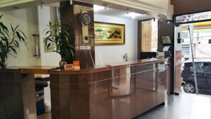 Una recepción con un reloj, un cuadro enmarcado y una planta en maceta.