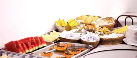 Een buffettafel met diverse etenswaren, zoals plakjes watermeloen, brood en gebak.