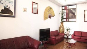 Una sala de estar con sofás rojos, un televisor y adornos en las paredes.