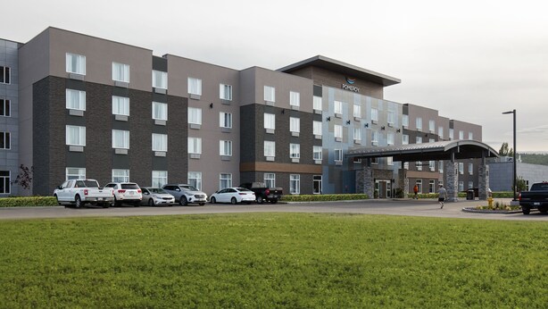 A multi-story hotel with a modern design, featuring a covered entrance and several parking spaces. - Pomeroy Inn & Suites Prince George (Prince George)