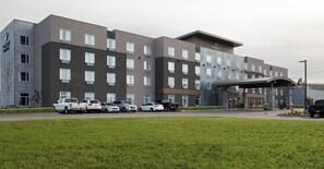 A multi-story hotel with a modern design, featuring a covered entrance and several parking spaces.