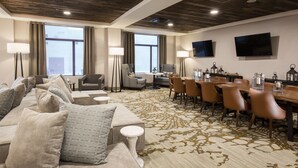 A hotel room with a large sofa set, a dining table with chairs, a flat-screen TV mounted on the wall, and a patterned carpet. - Pomeroy Inn & Suites Prince George (Prince George)