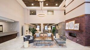 A spacious lobby with a modern design, featuring a seating area with sofas and chairs, a coffee table, and a fireplace. - Pomeroy Inn & Suites Prince George (Prince George)