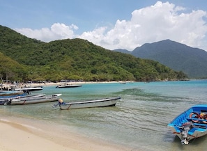 A beach with boats and a mountainous backdrop.