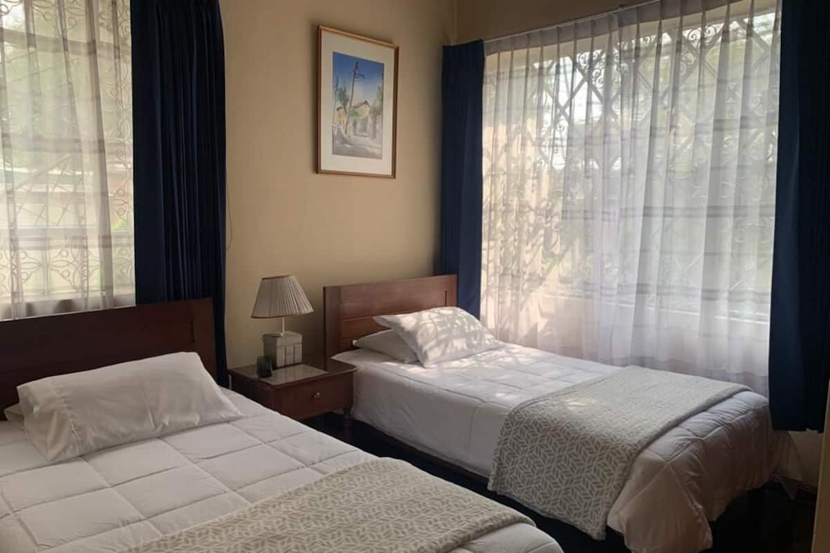 Ein Hotelzimmer mit zwei Betten, einem Nachttisch, einer Lampe und einem gerahmten Bild an der Wand.